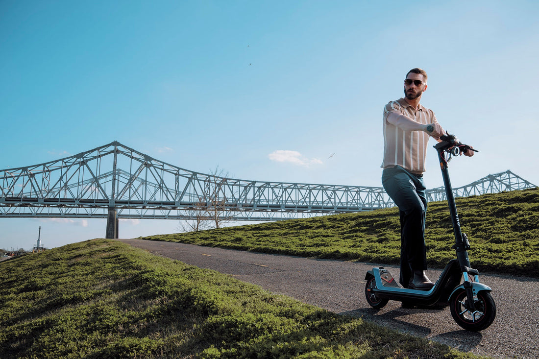 Hombre en scooter eléctrico NIU KQi300X junto a un puente