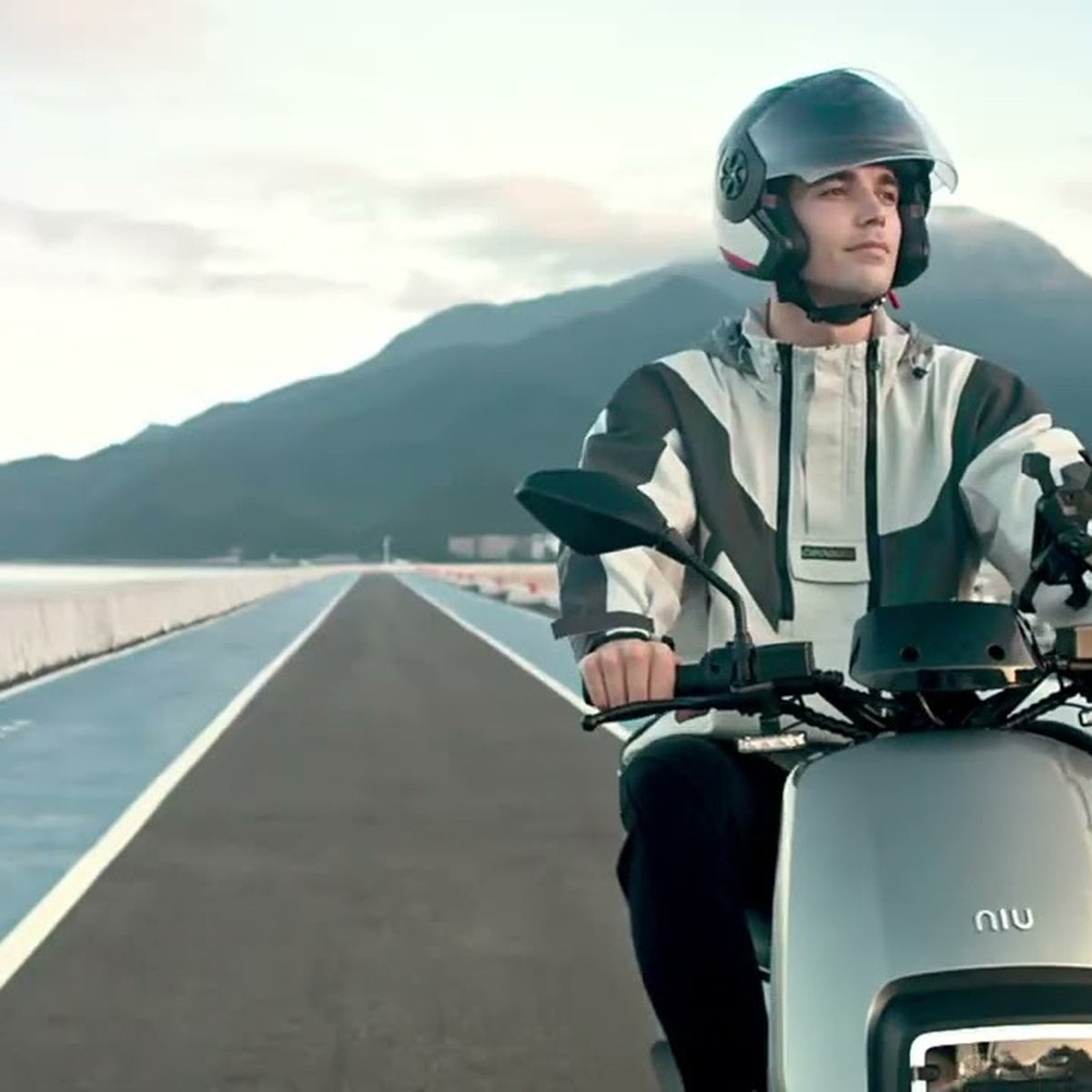 Motociclista en una moto eléctrica NIU por una ruta costera