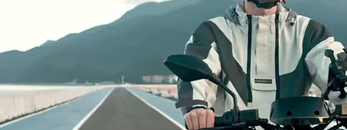 Motociclista en una moto eléctrica NIU por una carretera junto al cerro - E-Mobility Chile