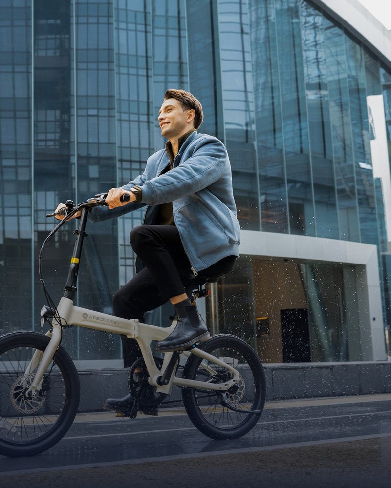 Hombre en bicicleta eléctrica plegable frente a un edificio de vidrio - E-Mobility Chile, Las Condes