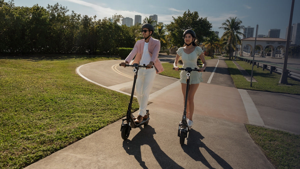 Pareja con casco recorriendo un parque en scooters eléctricos NIU - E-Mobility Chile, Las Condes