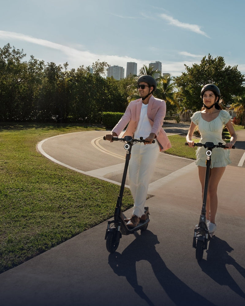 Pareja con casco recorriendo un parque en scooters eléctricos NIU - E-Mobility Chile, Las Condes