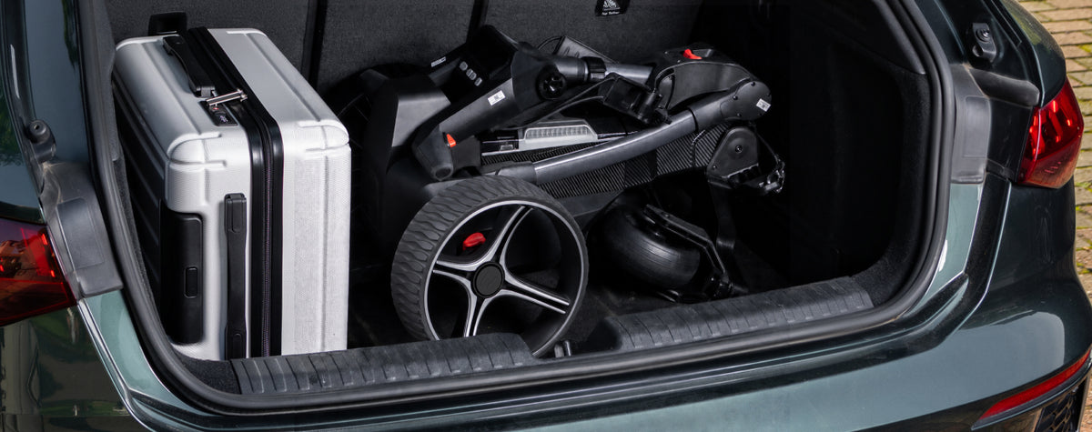 Carro de golf eléctrico NAVEE Birdie plegado en el maletero junto a una maleta de viaje - E-Mobility Chile