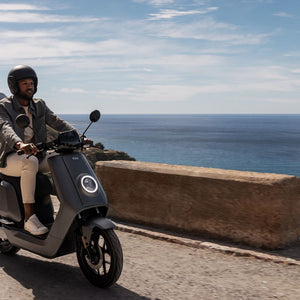 Moto Eléctrica NIU NQi GT blanca junto al borde costero - E-Mobility Chile, Las Condes