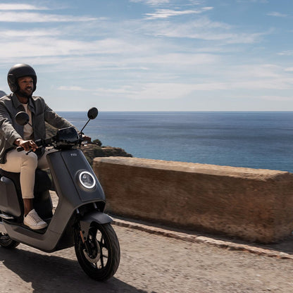 Moto Eléctrica NIU NQi GT blanca junto al borde costero - E-Mobility Chile, Las Condes